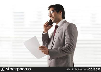 Smiling young businessman on phone call with a document