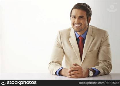 Smiling young businessman sitting at office desk