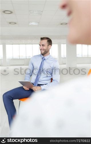 Smiling young businessman sitting with colleague during meeting at new office