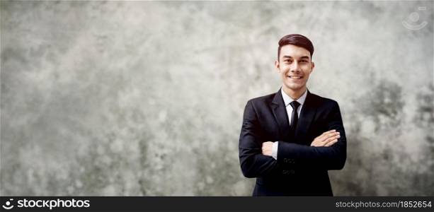 Smiling Young Businessman Standing by the Loft Concrete Wall. Crossed Arms and Looking at Camera. more copy space with Wide size