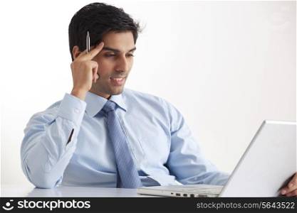 Smiling young businessman using laptop