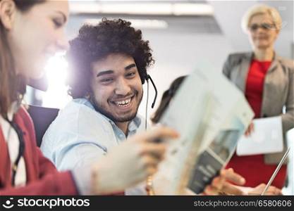 Smiling young businessman wearing headset with colleagues in office