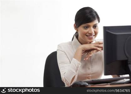 Smiling young businesswoman looking at computer