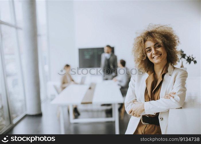 Smiling young businesswoman standing in modern office