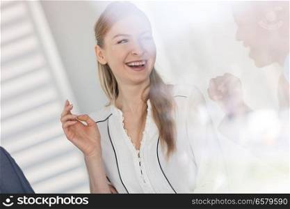 Smiling young businesswoman talking with male colleague in office