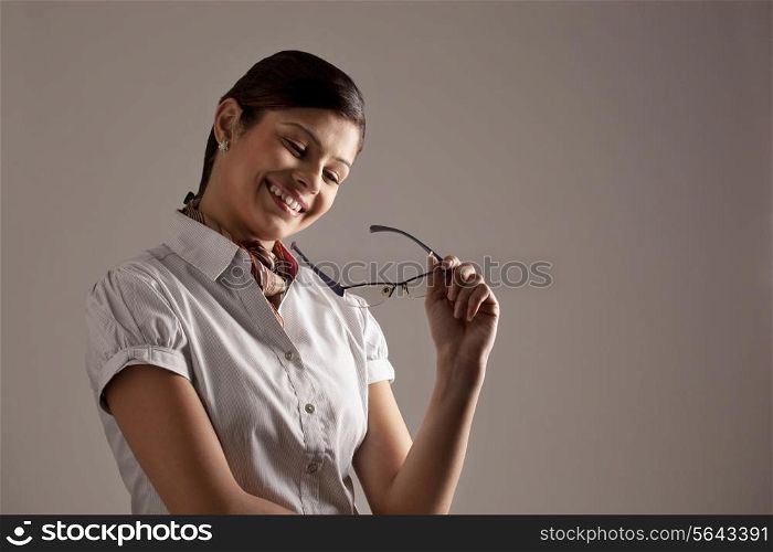 Smiling young businesswoman thinking while holding glasses
