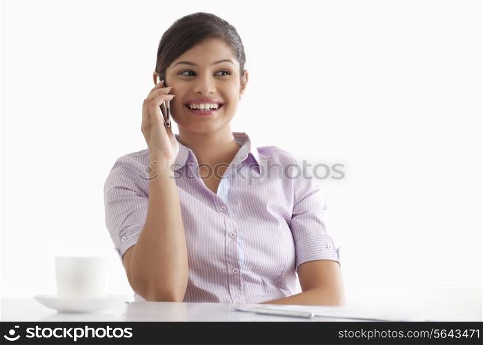 Smiling young businesswoman using cell phone at her desk