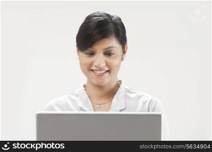 Smiling young businesswoman using laptop on white background