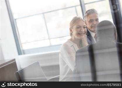 Smiling young businesswoman with male colleagues in meeting room