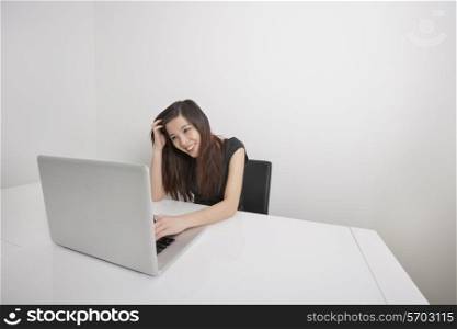Smiling young businesswoman working on laptop at office desk