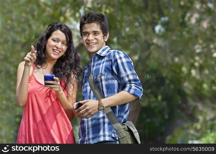Smiling young college friends with woman pointing at something interesting