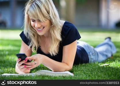 Smiling young college girl texting on a cell phone