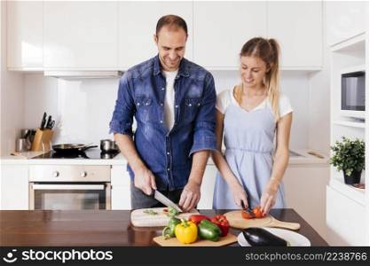 smiling young couple cutting vegetables with sharp knife kitchen