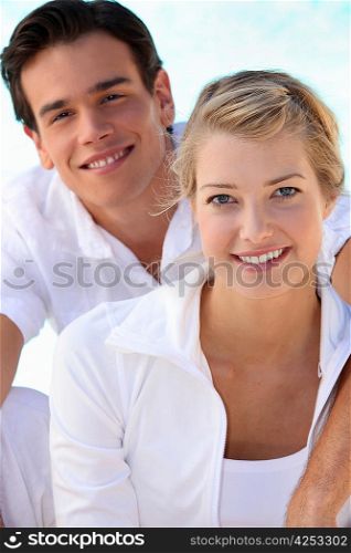 Smiling young couple dressed in white on a summer&acute;s day