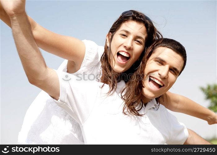 Smiling young couple holding hands eachother while piggyback