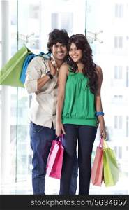 Smiling young couple holding shopping bags together
