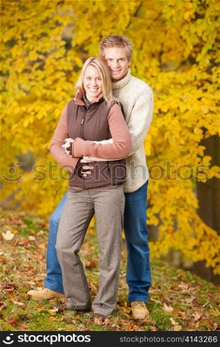 Smiling young couple in love hugging in autumn park together