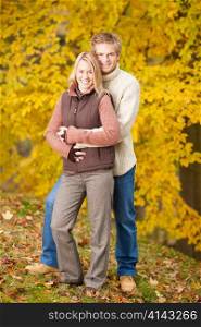 Smiling young couple in love hugging in autumn park together