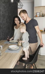 smiling young couple looking little boy standing chair serving oats plate breakfast