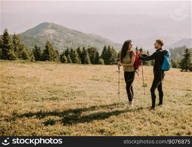 Smiling young couple preparing hiking adventure with backpacks by terrain vehicle