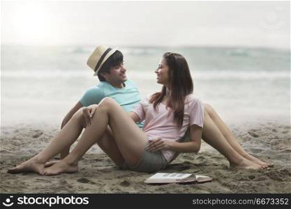 Smiling young couple sitting together on beach