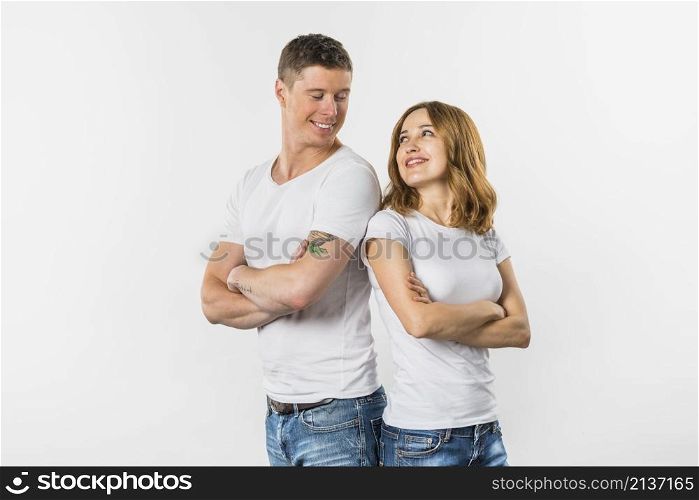 smiling young couple standing back back looking each other against white background