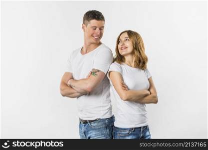 smiling young couple standing back back looking each other against white background
