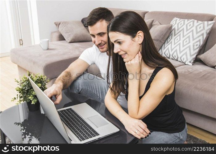 smiling young couple using laptop home