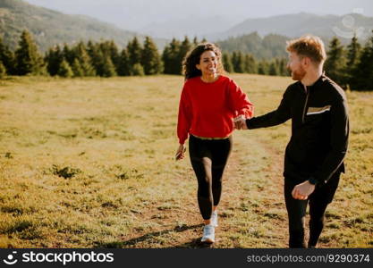 Smiling young couple walking over green hills