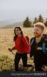 Smiling young couple walking with backpack over green hills