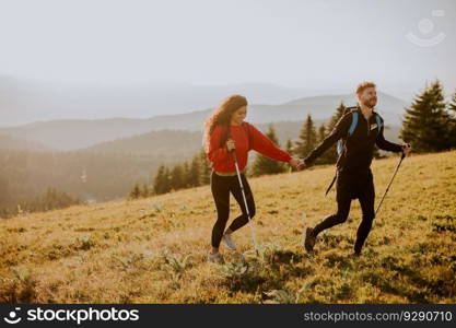 Smiling young couple walking with backpack over green hills