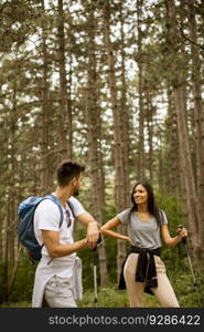 Smiling young couple walking with backpacks in the forest on a summer day