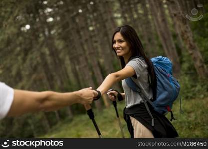 Smiling young couple walking with backpacks in the forest on a summer day