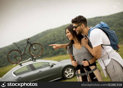 Smiling young couple walking with backpacks on a green hills at a summer day