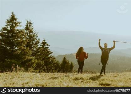 Smiling young couple walking with backpacks over green hills