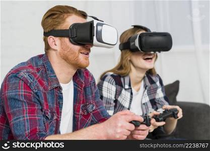 smiling young couple wearing reality goggles enjoying playing video game