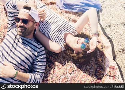 smiling young couple wearing sunglasses lying blanket