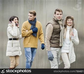 Smiling young couples walking against wall