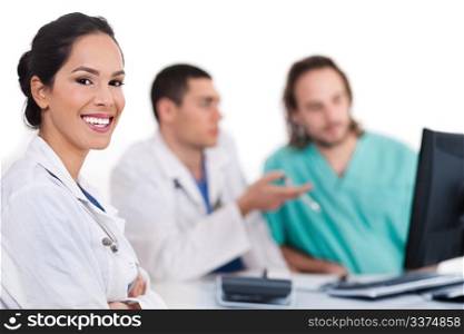 Smiling young doctor with other doctors behind her over white background
