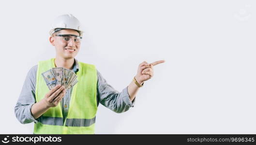 Smiling young engineer holding money pointing aside isolated. Handsome male engineer showing money pointing an advertisement isolated