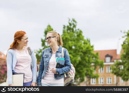 Smiling young female college friends walking outdoors