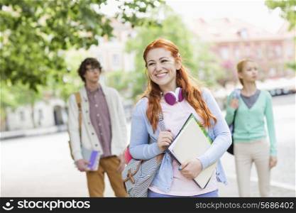 Smiling young female student with friends in background on street