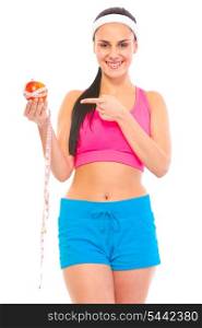Smiling young fit girl pointing finger on apple with measuring tape isolated on white&#xA;