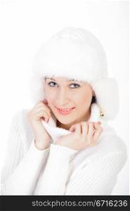Smiling young girl posing in a winter cap and knit sweater. Studio portrait on white background