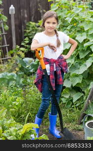 Smiling young girl working at garden with shovel