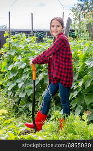 Smiling young girl working with shovel at garden