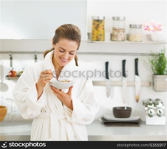 Smiling young housewife having healthy breakfast in modern kitchen