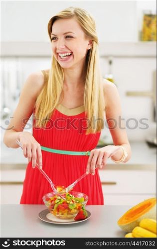 Smiling young housewife making salad