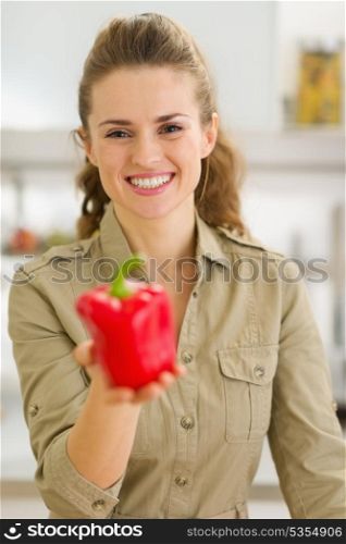 Smiling young housewife showing fresh red bell pepper