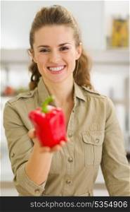 Smiling young housewife showing fresh red bell pepper